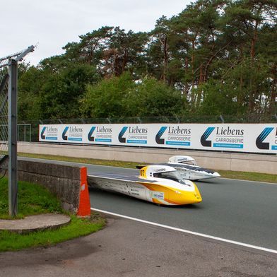 The Æthon solar cars in the foreground and the Adelie in the background on the racetrack in Zolder. (Source: Team Sonnenwagen)
