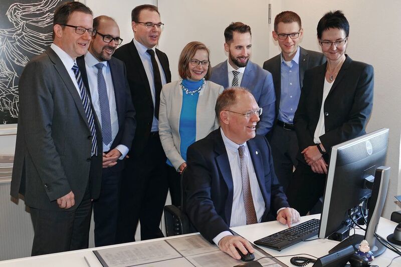 BfJ-Präsident Heinz-Josef Friehe unterzeichnet den ersten Vorgang in der E-Akte Bund (im Hintergrund Vertreter der am Pilotprojekt beteiligten Behörden und des Softwareherstellers) (BMI)