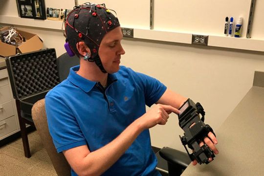 Das an der Washington University Schoof of Medicine in St. Louis (USA) entwickelte Gerät misst Hirnströme und wertet diese aus. In Reaktion auf die Signale öffnet und schließt eine daran gekoppelte Schiene die Hand des Trägers. (Bild:  Leuthard Lab / Washington University School of Medicine)