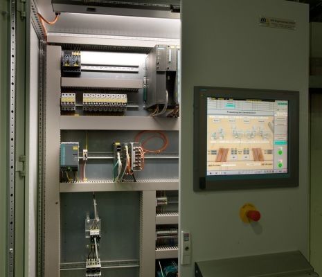 Bild 4: Die Automatisierungskomponenten für die Transportbühnen befinden sich im Schaltschrank der Pressenhalle. Zur Visualisierung wird ein im Schrank eingebauter, industrietauglicher Panel-PC eingesetzt, dem die Vibrationen durch die Pressen und die hohen Temperaturen in der Halle nichts ausmachen. (Bild: Siemens)