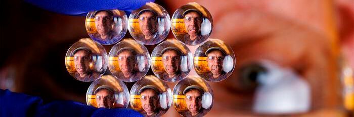 The visage of Stephen Morin, associate professor of chemistry, refracts through an array of lenses. Morin and his Nebraska colleagues have crafted much smaller lenses — some of them substantially narrower than a human hair — whose size and optical properties can be modified in seconds when subjected to certain stimuli. The visage of Stephen Morin, associate professor of chemistry, refracts through an array of lenses. Morin and his Nebraska colleagues have crafted much smaller lenses — some of them substantially narrower than a human hair — whose size and optical properties can be modified in seconds when subjected to certain stimuli.