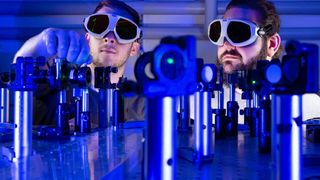 Besser als binär! Von links: Paul Herrmann und Sebastian Klimmer experimentieren an einem Laserversuchsaufbau an der Universität Jena, mit dem untersucht wird, wie man mit Licht und 2D-Materialien Informationen rund 1.000 Mal schneller übermitteln kann als mit Strom. (Bild: Uni Jena / J. Meyer)