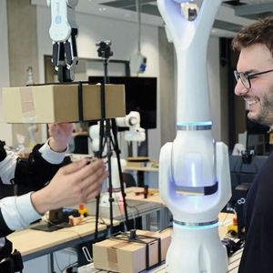 Federico Masiero (left, with exoskeleton) and Emanuele Aimi test collaboration with a robot from Neura Robotics. (Image:Andreas Schmitz / TUM)