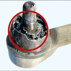 Dichtungsbalgschaden am Spurstangenendstück, verursacht durch Berührung mit Bremsflüssigkeit oder Motorenöl.