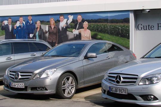 Gegenüber der Ausfahrt zeigt ein großes Plakat  einige Verkäufer und Servicemitarbeiter, die zum  Abschied winken. (Archiv: Vogel Business Media)