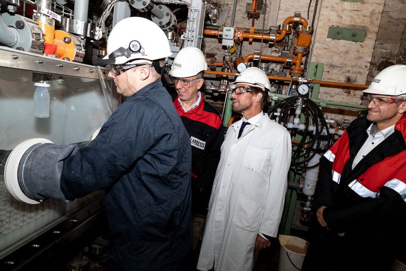 Michael Ertl, Leiter Benzyl Produkte und Anorganische Säuren bei Lanxess, zeigt Leverkusens Oberbürgermeister Uwe Richrath und Hubert Fink, Vorstandsmitglied von Lanxess (v.r.n.l), die Probenentnahme im Schwefelsäurebetrieb in Leverkusen. (Lanxess)