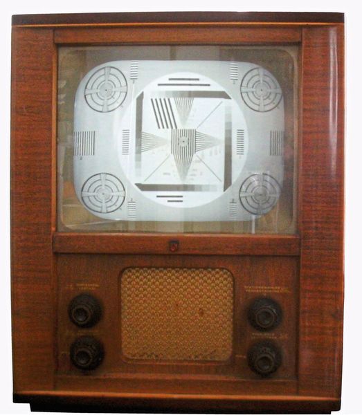 1952: Testbild auf dem Philips TD1410U. Im Volksmund hieß dieser Röhrenfernseher wegen der Gehäuseform Starenkasten. Er gehörte zu den ersten Fernsehgeräten der Nachkriegszeit, produziert von Philips in Deutschland wenige Monate vor dem offiziellen Start des deutschen Fernsehens (25.12.1952). 24 Röhren und ein 625-Zeilen-Abtastverfahren des HF-Teils brachten die Bewegtbilder auf die Kathodenstrahlröhre. Zur Speisung der Zeilenablenkeinheit sorgte der Zeilentrafo mit 9.000 V Anodenspannung. Widerstände und Kondensatoren  waren unter dem Chassis von Hand frei verdrahtet/verlötet. Zur Beurteilung der Bildqualität diente ein Testbild in der sendefreien Zeit. Die geometrischen Figuren des Testbildes erlaubten das Prüfen und Justieren von z. B. Bildgeometrie, Schärfe, Bildschatten, Gradation. Heute sieht man Testbilder, wenn eine Störung vorliegt.  (Bild: Yagosaga, CC BY-SA 2.0 DE)