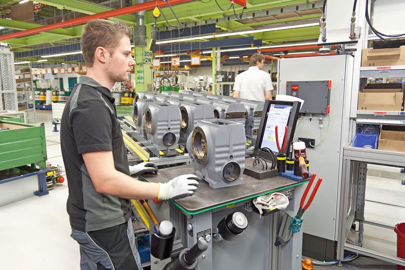 Kernbereiche der Montage sind modular aufgebaute u-förmige Montagezellen. Innerhalb dieser Montage­inseln fungieren mobile Logistikassistenten als mobile Werkbank, welche die einzelnen Arbeitsstationen anfahren und sich dabei auf die ideale Arbeitshöhe einstellen.  (SEW-Eurodrive)