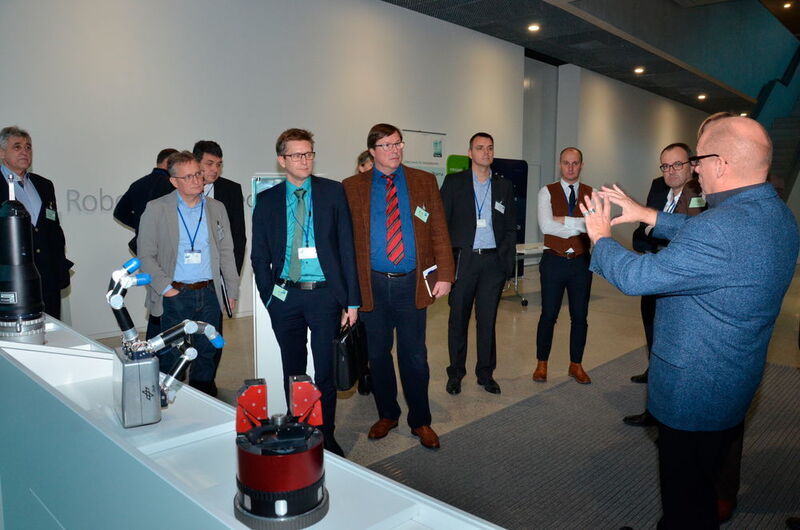 Peter Meusel (r.), DLR-Mitarbeiter und Mitgründer des Start-ups Wessling Robotics, erklärt die Geschichte der am RMC entwickelten Roboterhände. (Forum MedTech Pharma e.V. / DLR)