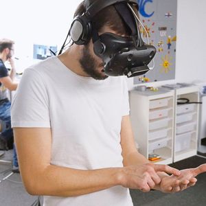 Ein Teilnehmer gibt auf seiner realen Handfläche virtuelle Zahlenwerte ein. Das Experiment wird im Hintergrund von Dominic Gottwalles überwacht.