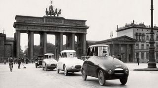 Ein historisches Foto von drei Stromlinien-Limousinen von Paul Jaray, die 1923 in Berlin in einer Reihe durch das Brandenburger Tor fahren: Der Ley 6/16 PS Typ T6, der bereits 1922 gebaut wurde, führt die Reihe an. Es folgen der Audi 14/35 PS Typ C und der Dixi 6/24 PS von 1923. (Bild: Audi AG)