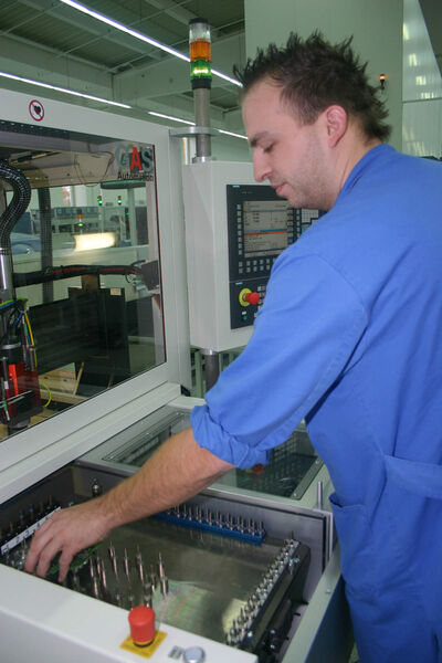 Die Verbindungsstege sind getrennt: EWA-Systembetreuer Matthias Prögel kann die einzelnen Leiterplatten aus der Maschine nehmen. (Siemens)