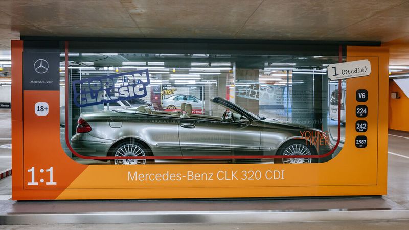 Begleitende Inszenierung des Vision CLK 320 CDI (Baureihe 209) von 2005 in einem der großen Glaskuben im Museumsparkhaus. Dort sind insgesamt fünf Youngtimer im Stil von Modellautos in einer überdimensionalen „Verkaufsverpackung“ zu sehen.  (Bild: Mercedes-Benz AG)