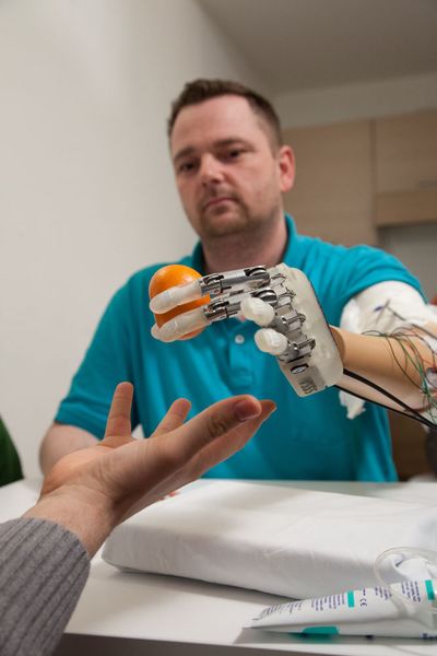Greifen und fühlen wie mit einer echten Hand: Der Patient Dennis Aabo Sørensen greift mit seiner künstlichen Hand eine Mandarine. (IMTEK, Universität Freiburg )