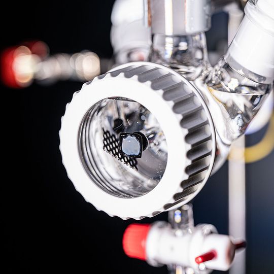 Die photoelektrochemische Schlenk-Zelle im Sonnensimulator. Die rechteckige, graue Fläche mit schwarzer Einrahmung im Vordergrund ist die photoelektrochemische Solarzelle. (Bild:  Valentin Marquardt / Universität Tübingen)