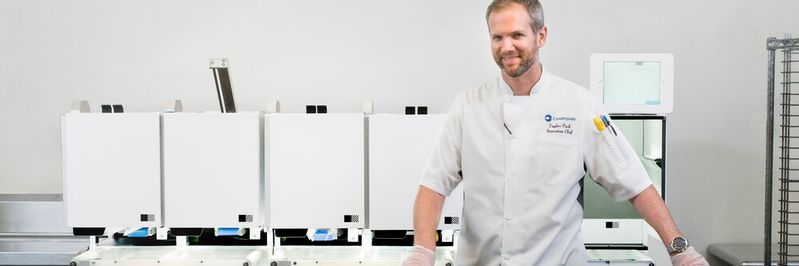 Taylor Park, CEO des US-Cateringunternehmens Centerplate, steht vor dem automatischen Pizza-Roboter von Picnic im T-Mobile Park, der Heimat der Seattle Mariners. Teilnehmer der CES 2020 können am Picnic-Stand die vom Roboter produzierte Pizza genießen. (Bild:  Kyu Han/Picnic)