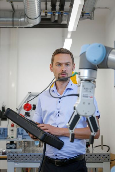 Stefan Trabesinger, Mitarbeiter am Institut für Fertigungstechnik der TU Graz, arbeitet mit einem kollaborativen Roboter in der Fabrik. (Bild: Lunghammer / TU Graz)