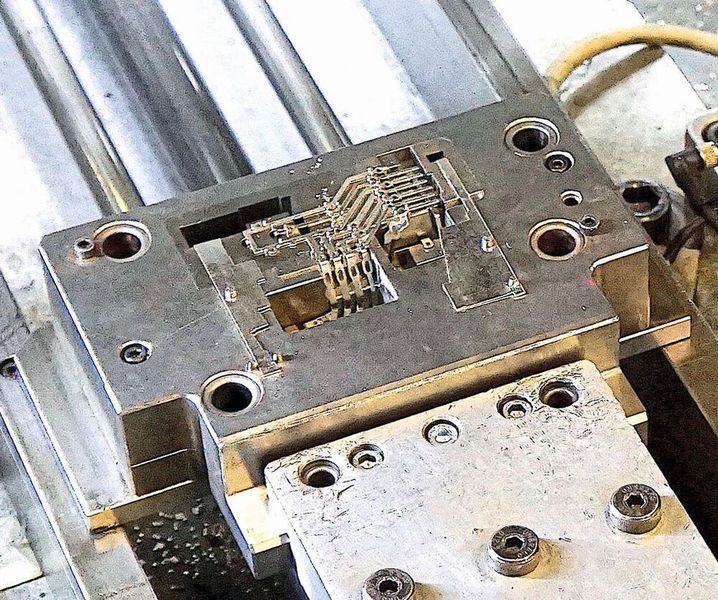 Bild 6: Komplexe dreidimensional geformte Leiterbahnstrukturen werden direkt aus der Stanz-Biege-Anlage von einem Roboter an die Rundtischmaschine übergeben. (Wittmann-Battenfeld)