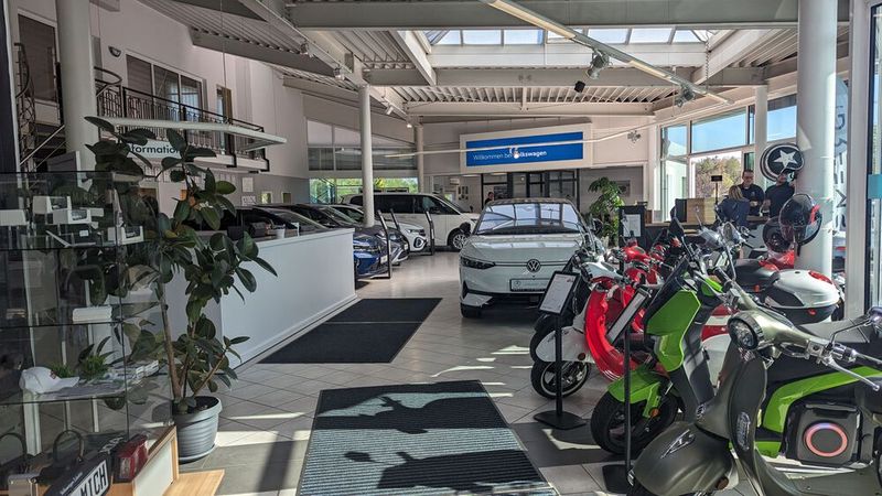 Vom Autohaus zum Mobilitätsdienstleister: Das hat sich das Autohaus Rudolph mit Sitz in Oelsnitz im Erzgebirge auf die Fahne geschrieben, die nächste Station der Juryrundreise. Sichtbar ist das auch im Showroom, wo sich E-Roller von Dreems aneinanderreihen. (Bild: Simon – VCG)