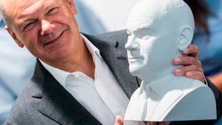 Bundeskanzler Olaf Scholz (SPD) fasst sich buchstäblich an den Kopf! Denn im Rahmen seines Besuchs beim Hasso-Plattner-Institut bekam er eine Büste von sich überreicht, die man dort per additiver Fertigung hergestellt hat. (Bild: dpa)