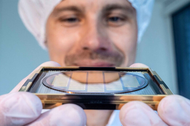 Einer der Q.ANT-Mitarbeiter präsentiert einen Wafer, aus dem die photonischen Chips geschnitten werden.  (Trumpf)