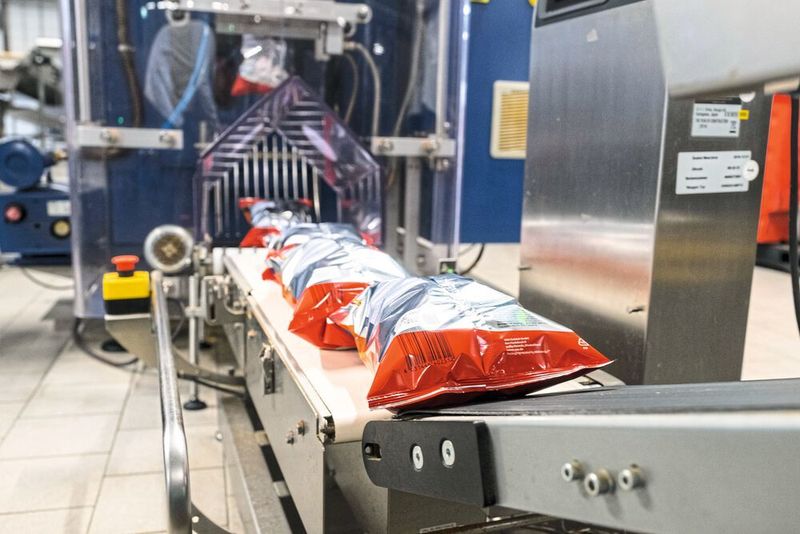 Verkaufsfertige Schlauchbeutel mit würzigem Inhalt verlassen die Wolf Verpackungsmaschine in Richtung Kartonierer. (Lenze)