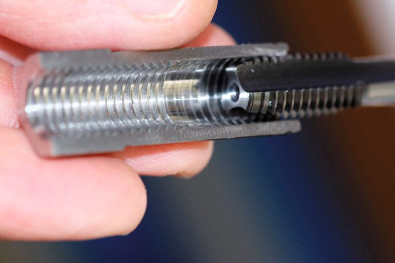 Blick auf den Fertigungsprozess ab Stange und auf die aufgeschnittene Gewindebuchse. Der Gewindeschneider muss zirka 20 mm in das Werkstück eintauchen, bevor es ans Zerspanen geht. Dank Sackloch (ab Stange) und 20 bar-Hochdruckkühlung werden die Späne sicher aus der Prozesszone nach hinten abgeführt. (Bild: Matthias Böhm)
