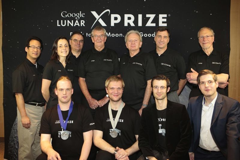 Die Part-Time Scientist von links nach rechts: Arne Reiners (Universal Genie, verantwortlich für die Kamera) , Karsten Becker (Elektronik und Öffentlichkeitsarbeit), Thomas Schachner (Elektronik) und Robert Böhme (Teamleiter). Im Hintergrund die Expertenjury (Foto: Google Lunar X-Prize)