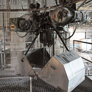 Entlang eines Schienensystems laufen Greifer, die nach und nach die Rohstoffkeller anfahren, bis das richtige Mischungsverhältnis des Pegmatitsands erreicht ist.  (Bild:  Shamika Löchel, BAM GmbH)