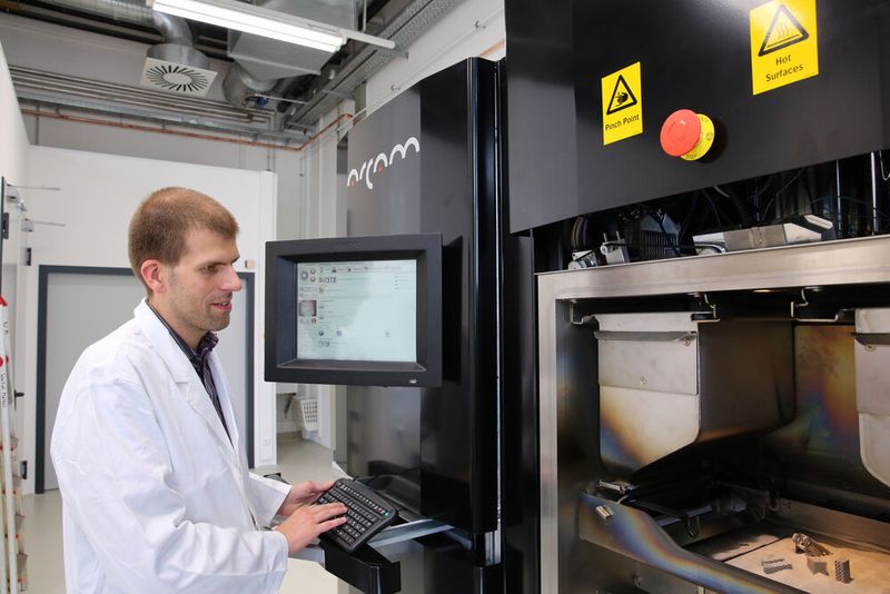 Prof. Dr. Thomas Niendorf mit einem 3D-Metalldrucker (und älteren Produkten). ( Andreas Fischer)