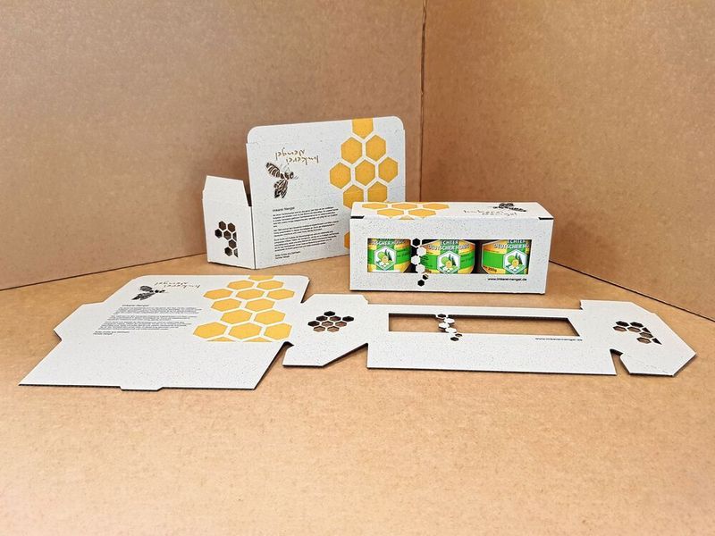 Kategorie „Gestaltung & Veredelung“: Die Präsentverpackung ist eine Faltschachtel in geringer Auflagenhöhe, die als Sammelpackung für drei Honiggläser dient. Um die Nachhaltigkeit und Naturnähe des Honigs zu unterstreichen, wird als Packstoff Wellpappe verwendet, die einen bis zu 40-prozentigen Anteil von Grasfasern aufweist. Zudem wurden mit Laserstanztechnologie sehr feingliedrige und filigrane Stanzbilder auf der Wellpappschachtel umgesetzt. (DVI/ Heuchemer Verpackung GmbH & Co. KG)