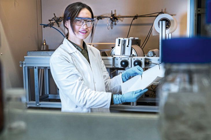 Zhenzhen Zhang präsentiert die Herstellung der Membran mit der institutseigenen Membranziehmaschine (im Hintergrund) (Bild: HZG/Steffen Niemann)