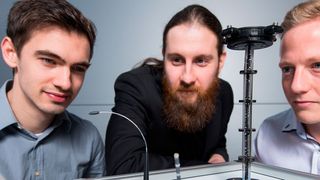Die Doktoranden Dominik Scholtes (l.), Rouven Britz und Yannik Goergen (r.) aus Prof. Stefan Seeleckes Team mit Prototypen der biegsamen Roboterarme, die auf der Hannover Messe zu sehen sein werden. (Oliver Dietze)