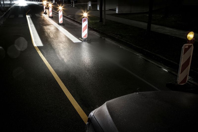 In engen Baustellendurchfahrten beispielsweise wird der Fahrer gezielt per Lichtschiene geführt. Dazu wird eine Lichtspur auf die Straße projiziert, die dem Fahrer die Fahrzeugbreite anzeigt und ihn sicher leitet.  (Bild: Daimler AG)