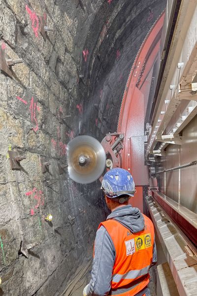 Auf der Außenseite des Vortriebsportals befindet sich eine besondere Schneidapparatur: Die Sägen fahren im Bogen an der Tunnelwand entlang und zerteilen sie.  (Bild: ARGE EET)