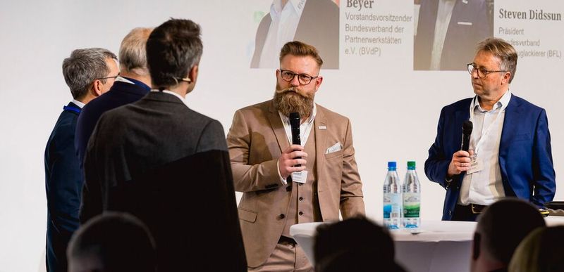 Bei der Podiumsdiskussion mit dem Titel „Berufsbilder im Zeitalter von KI und Robotik“ wird auch Steven Didssun (Bildmitte), Präsident des Bundesverband Fahrzeuglackierer, einen Part übernehmen. (Bild:  Stefan Bausewein)