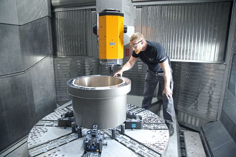 Maschinenbediener Joel Schmid beim Prüfen eines Drehteils. Bei dem Bauteil handelt es sich um ein Hybrid-Gleitlager, bei dem für den Gleitlagerbereich eine Bronzebuchse eingegossen wurde. Dieses Bauteil wurde ausserhalb der Maschine ausgerichtet. (Bild: Matthias Böhm)