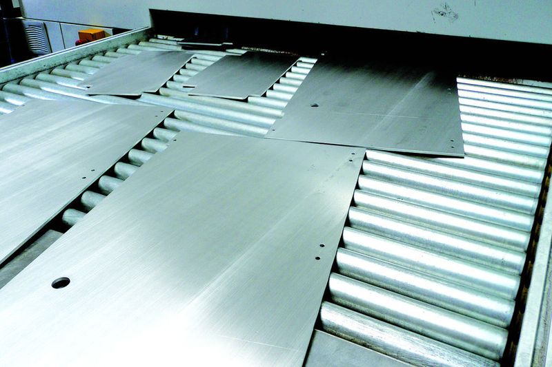 Die fertig bearbeiteten Bleche auf dem Auslaufförderband der Ernst EM 5N II + 2; jetzt sind die Kanten entgratet und verrundet – ohne Beeinträchtigung der Oberflächenstruktur. (Archiv: Vogel Business Media)