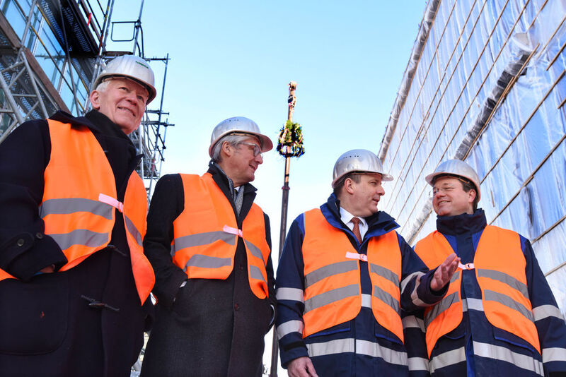 Architekt Gunter Henn, OB Jochen Partsch, GL-Mitglied Kai Beckmann und Standortleiter Matthias Bürk mit dem Richtkranz im Hintergrund. (Merck/Claus Voelker)
