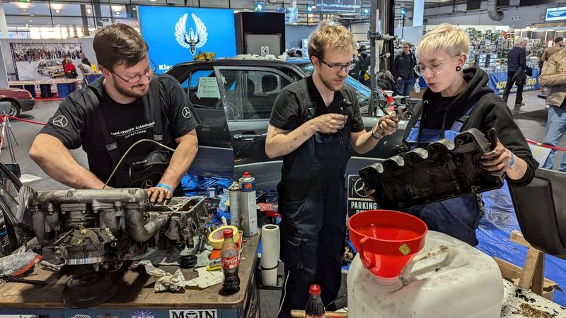 Ja, das sind junge Männer und eine junge Frau, und ja, sie haben echte Schrauberhände: Live-Zylinderkopfschrauben am W124 während der Messe. (Bild: Dominsky – VCG)