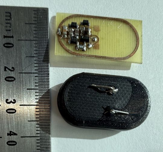 Prototyp des ECHO-Implantats: oben die Platine mit Empfangsspule und Regelelektronik, unten das 3D-gedruckte Gehäuse mit zwei Anschlüssen für den Katalysator. Maßstab in Millimetern.(Bild:  Maity und Fussenegger, ETH Zürich)