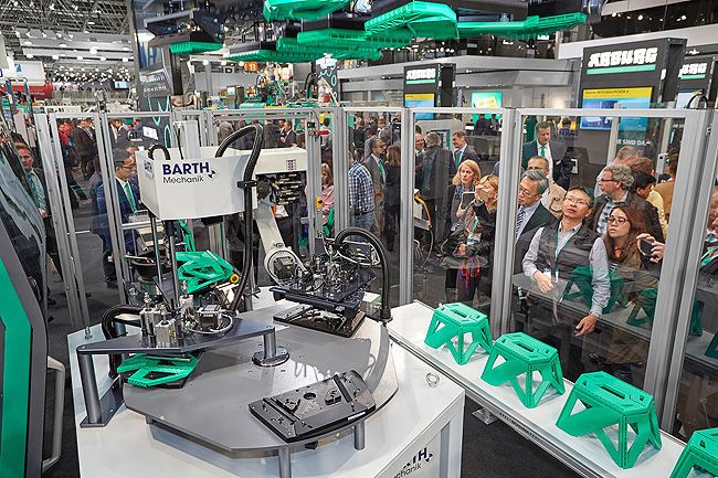 Eine weitere Turnkey-Anlage auf der Fakuma dreht sich rund um die hybride Großmaschine Allrounder 1120 H mit 6500 kN Schließkraft. Sie fertigt acht Einzelteile an, die zu einem gebrauchsfertigen, klappbaren Trittschemel zusammenmontiert werden. (Arburg)