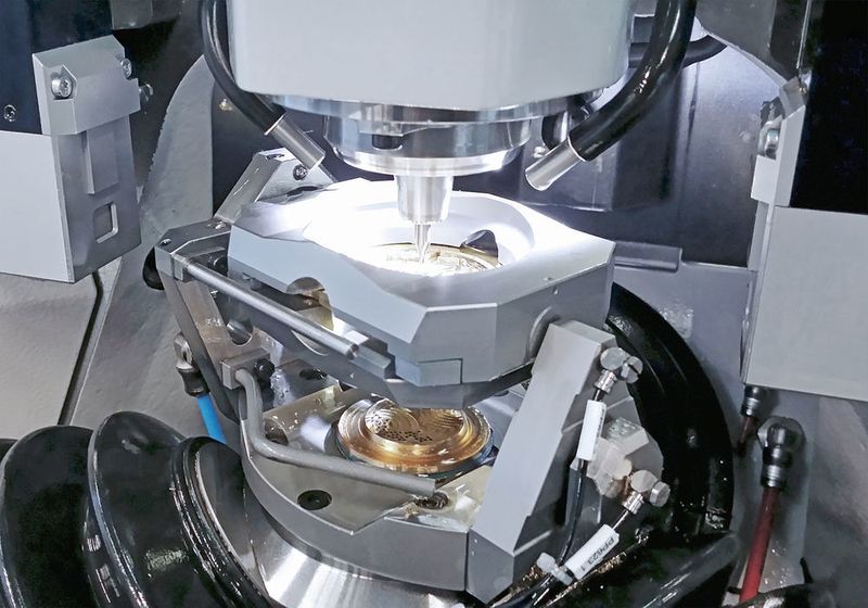 La taille des pièces typiques pour la 701S est de diamètre 50 mm pour une hauteur de 30 mm. Equipée du serrage recto-verso Willemin-Macodel, la machine peut usiner dans le même serrage les 2 côtés d’une barquette ainsi que le trou de tige à 90°. (Willemin-Mocodel)