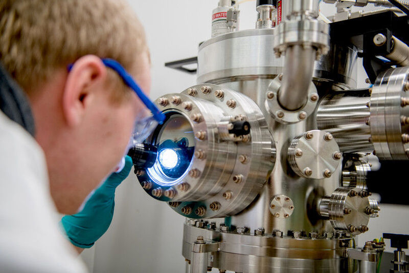 Michael Meischein vor dem Sputter-System, in dem die Nanopartikel durch simultane Beschichtung aus mehreren Quellen in einer ionischen Flüssigkeit erzeugt werden. (RUB, Marquard)