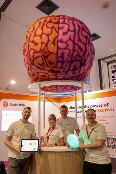 BrainTrip Ltd stellte NeuroAI vor: Es erleichtert die Verarbeitung von Gehirnwellendaten, liefert einfache Ergebnisse und unterstützt so die Diagnose von Hirnerkrankungen, wie ADHS, Demenz, Depressionen. Zu sehen das Team am Stand mit David Sakić, Co-founder und CEO (links).  (©Messe Berlin GmbH)