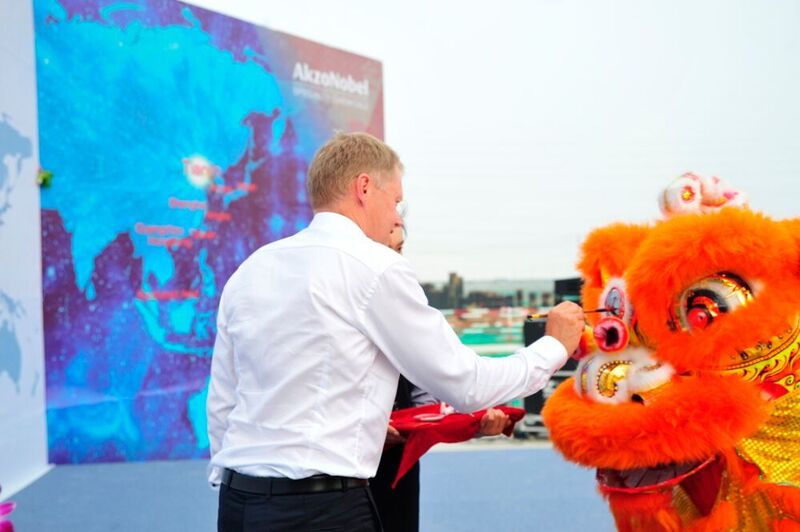 An executive committee member dots the eyes of a lion for the success of the new site.   (Akzo Nobel)