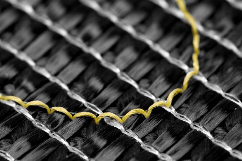 GFK-Profil mit integrierter faseroptischer Sensorik: Eine Sensorfaser (dünn und transparent, fixiert vom gelben Aramidfaden) wurde direkt während des Pultrusionsprozesses in das Faserverbundbauteil integriert. Damit ist eine sensorische Überwachung des GFK-Bauteils möglich.  (Bild: ITV Denkendorf)