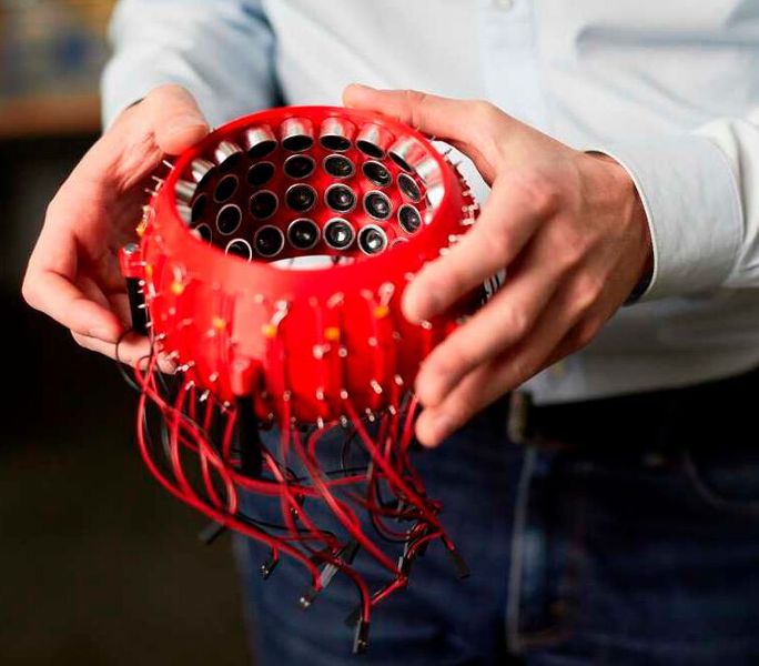 In zwei mittels 3D-​Druck hergestellten Halbkugeln hat Marcel Schuck zahlreiche Mini- Lautsprecher eingebaut. Mit Hilfe einer Software kann er diese so ansteuern, dass sich die Druckpunkte, in denen die kleine Objekte gefangen gehalten werden, verschieben lassen. (ETH Zürich/Stefan Weiss)
