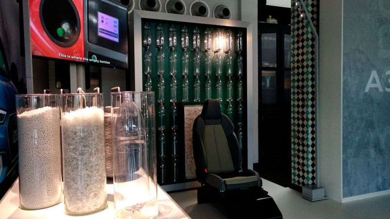 PET-Flaschen und das daraus erzeugte Granulat. Es wird anschließend eingeschmolzen, gehäckselt und zu Fasern extrudiert – die dann zu Fäden der Sitzgarnitur oder des Teppichs versponnen werden. (Bild: Thomas Günnel/Automobil Industrie)