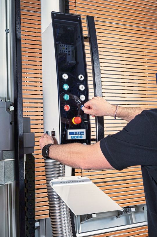 Die Zweihandbedienung der vertikalen Säge vermeidet die Verletzungsgefahr beim Positionieren der Holzplatten für den Zuschnitt. Das magnetische Messprinzip der Messanzeige eignet sich für raue Umgebungen. (Bild:  Striebig AG)